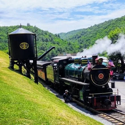 A vintage steam train traveling through a green mountain valley