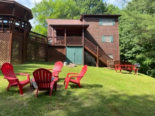 Red Adirondack chairs on the lawn near a rustic mountain cabin